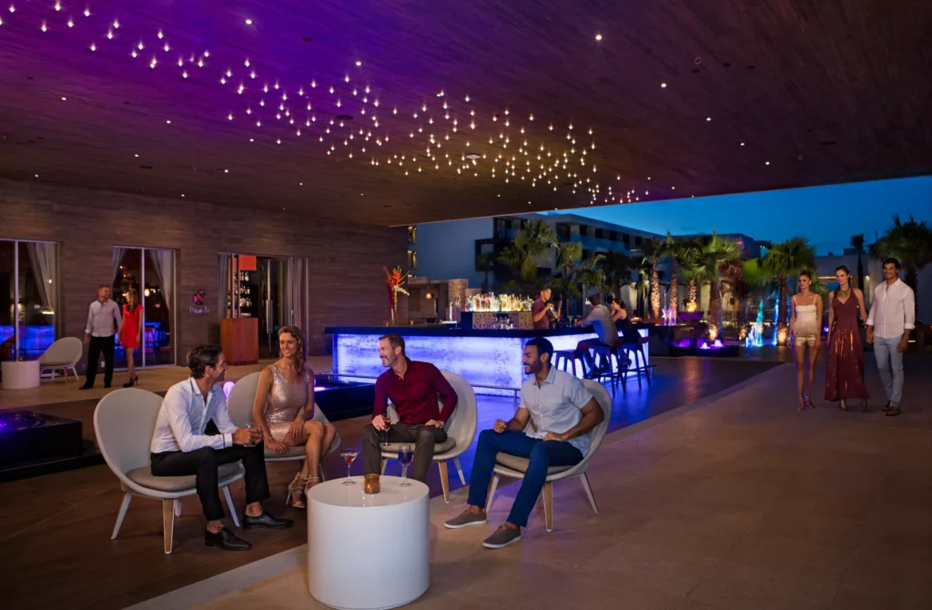 Wink cocktail bar at Secrets Riviera Cancun featuring illuminated bar, top-shelf spirits, and vibrant evening lounge atmosphere.