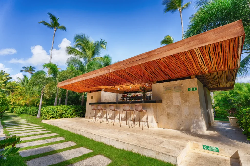 Drifters Lazy River Pool Bar at Secrets Royal Beach Punta Cana featuring a modern open-air bar surrounded by tropical gardens.