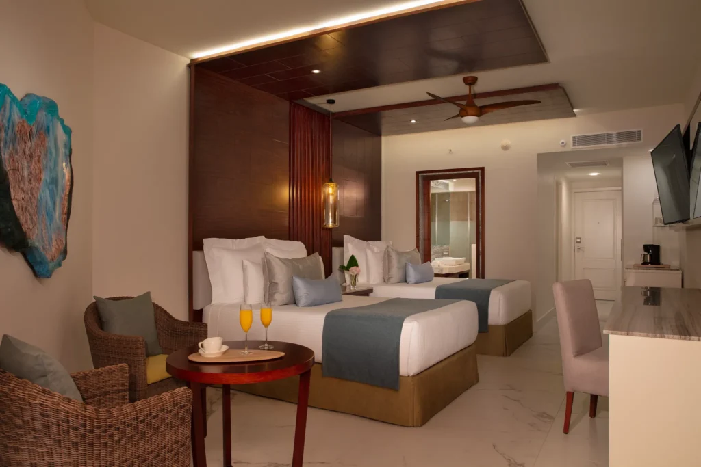 Junior Suite Pool View with two double beds and seating area at Secrets Royal Beach Punta Cana.