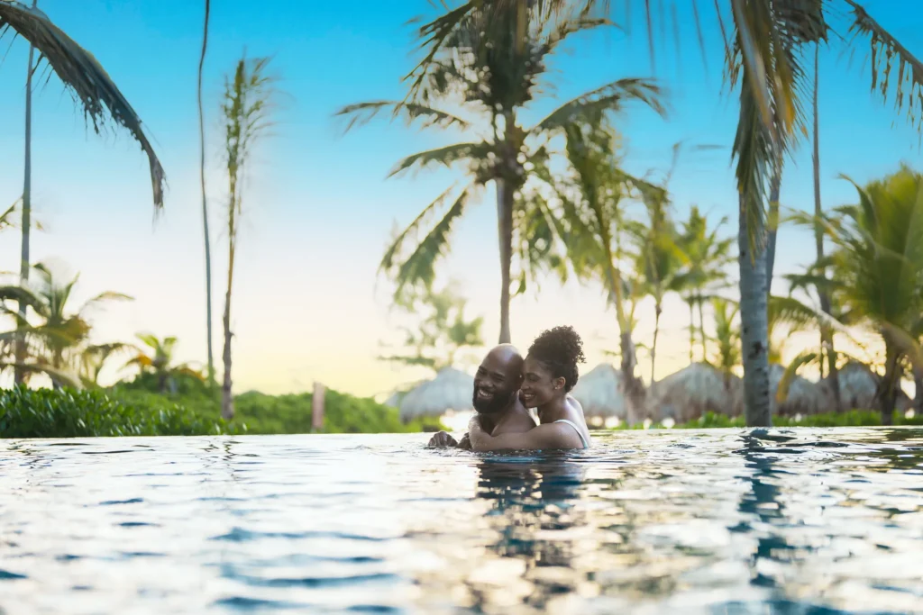 Romantic couple embracing in the infinity pool at sunset at Secrets Royal Beach Punta Cana.
