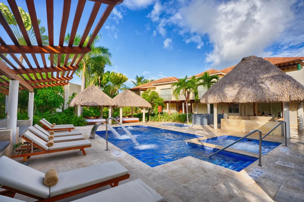 Outdoor hydrotherapy spa pool with loungers and palapa huts at Secrets Royal Beach Punta Cana in the Dominican Republic.