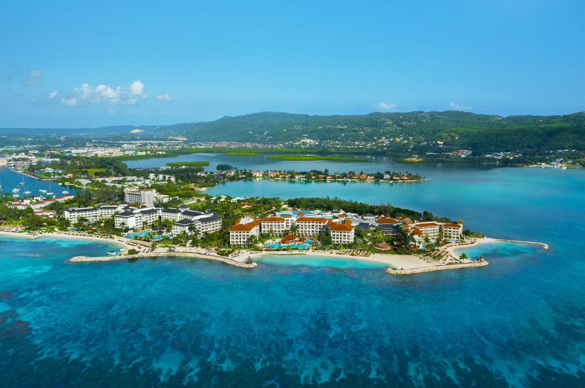 Aerial view of Secrets St. James Montego Bay surrounded by turquoise Caribbean waters and a private peninsula in Jamaica.