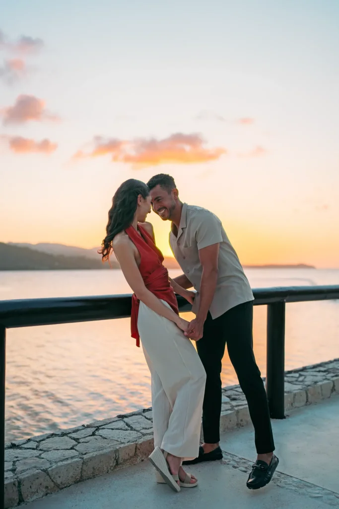 Couple holding hands and laughing during a sunset walk overlooking the ocean at Secrets St. James Montego Bay.