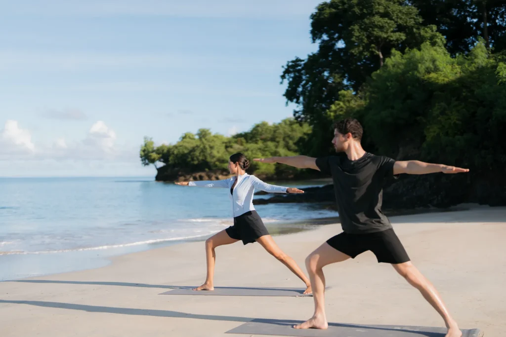 Couple practicing yoga on the beach at Secrets St. Lucia Resort & Spa with ocean views.
