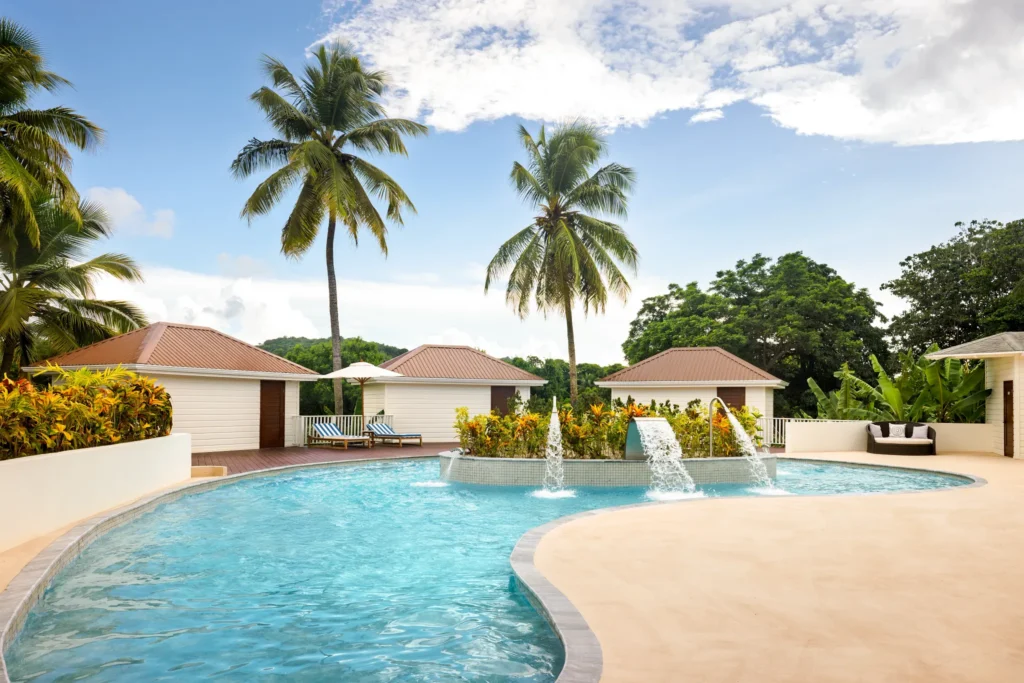 Tropical hydrotherapy pool with water features at Secrets St. Lucia Resort & Spa, surrounded by palm trees and private cabanas.