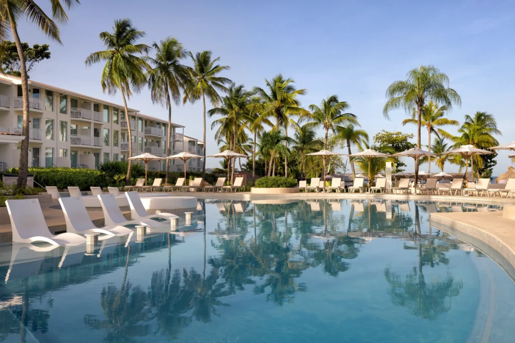 Large resort pool with lounge chairs and palm trees at Secrets St. Lucia Resort & Spa.