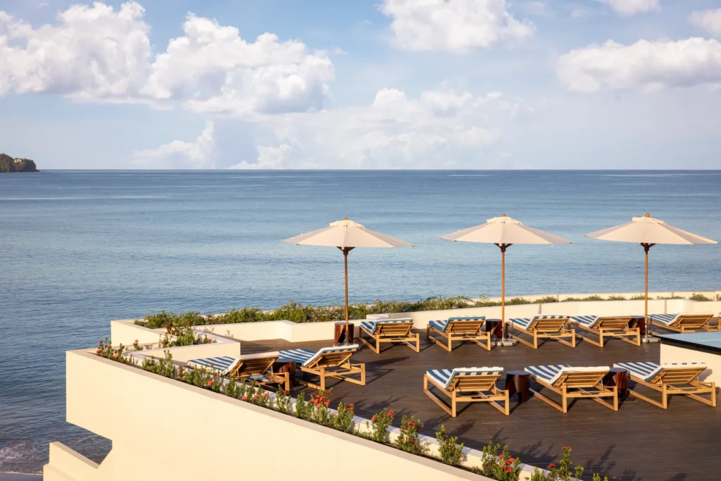 Oceanfront deck with lounge chairs and umbrellas overlooking the Caribbean Sea.