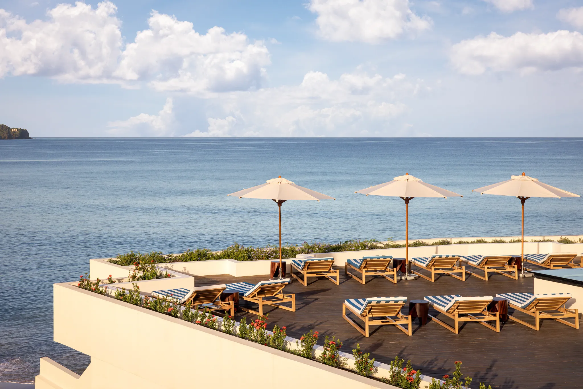 Oceanfront deck with lounge chairs and umbrellas overlooking the Caribbean Sea.