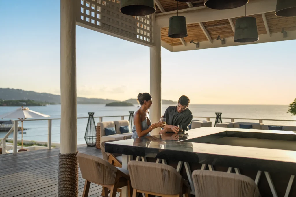 Couple enjoying drinks at an oceanview bar terrace at Secrets St. Lucia Resort & Spa during sunset.