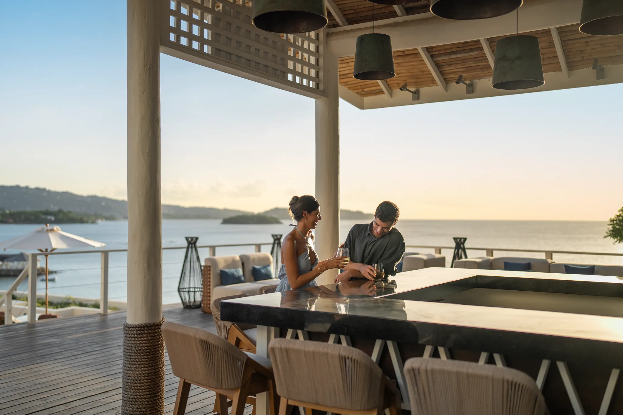 Couple enjoying drinks at an oceanview bar terrace at Secrets St. Lucia Resort & Spa during sunset.