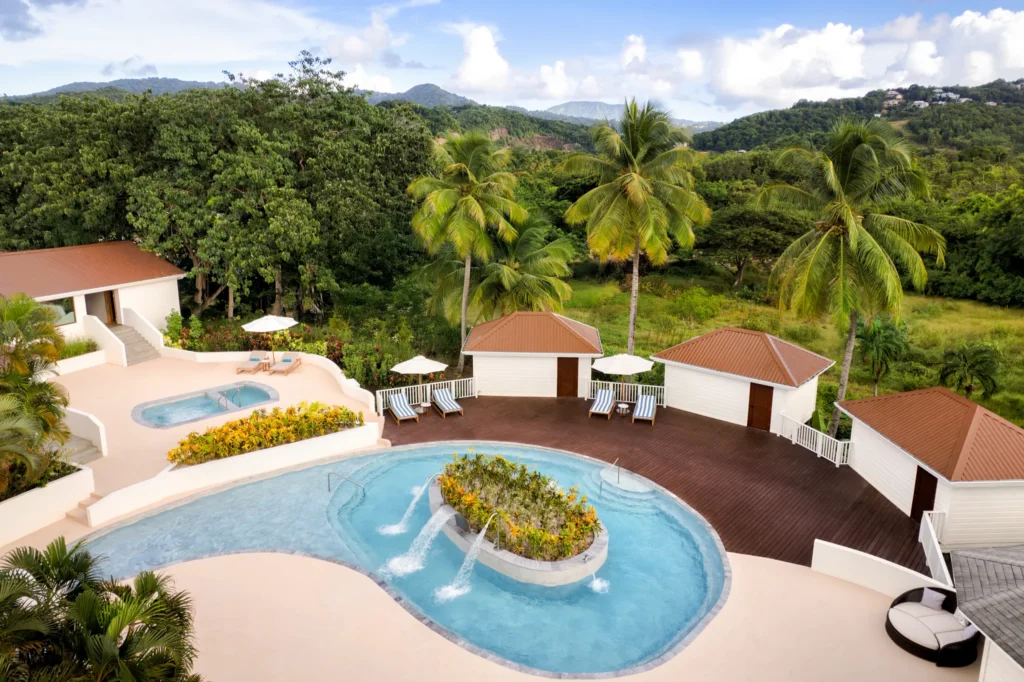 Elevated view of hydrotherapy spa pool and cabanas at Secrets St. Lucia Resort & Spa, overlooking lush tropical hills.