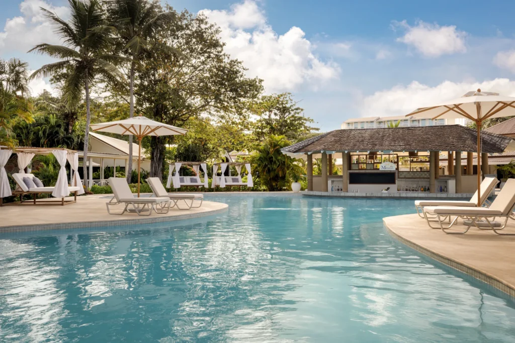 Resort pool with swim-up bar, loungers, and private cabanas at Secrets St. Lucia.
