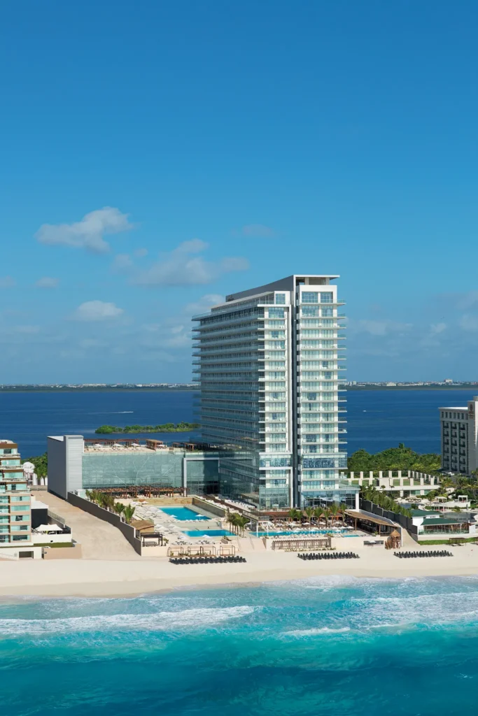Aerial perspective of Secrets The Vine Cancun resort tower overlooking the Caribbean Sea and surrounding hotels.