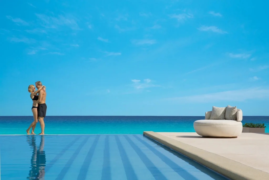 Couple embracing in an infinity pool with panoramic ocean views at Secrets The Vine Cancun, ideal for couples and honeymooners.