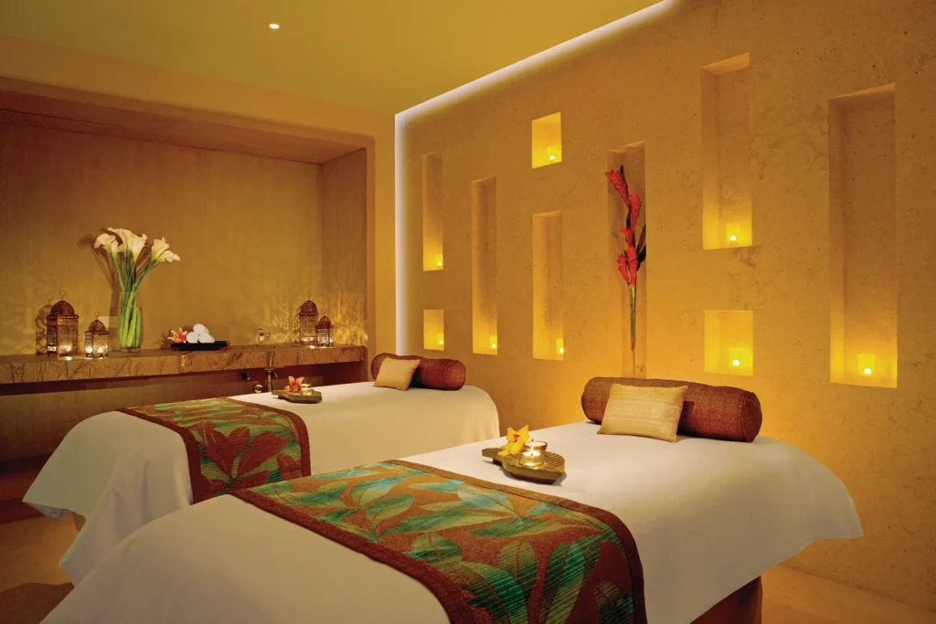 Couples massage room with two spa beds and warm lighting at Secrets The Vine Cancun.