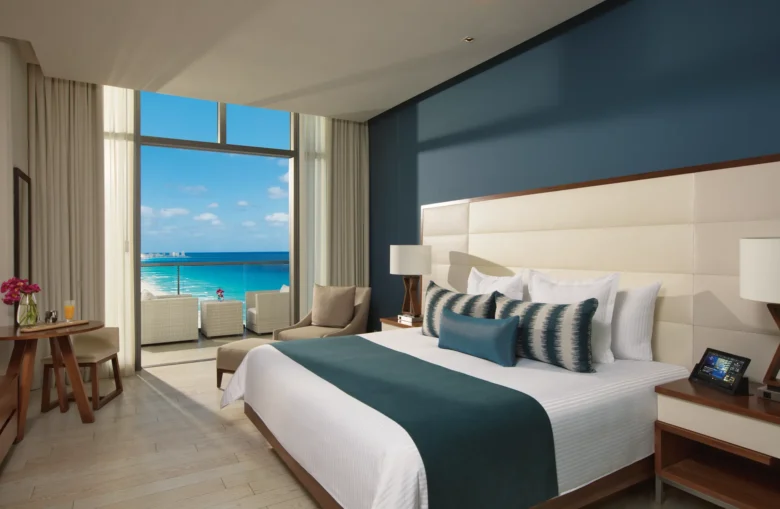 Deluxe Ocean View room with king bed and furnished balcony overlooking the turquoise Caribbean at Secrets The Vine Cancun.
