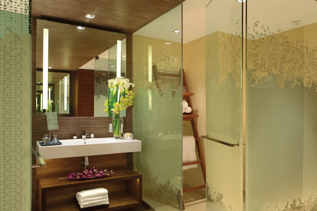 Deluxe Partial Ocean View bathroom with glass-enclosed shower and modern vanity at Secrets The Vine Cancun.