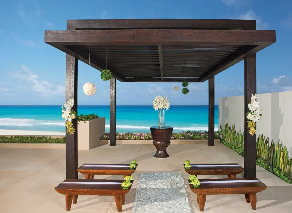 Oceanfront gazebo wedding ceremony setup with wooden pergola at Secrets The Vine Cancun