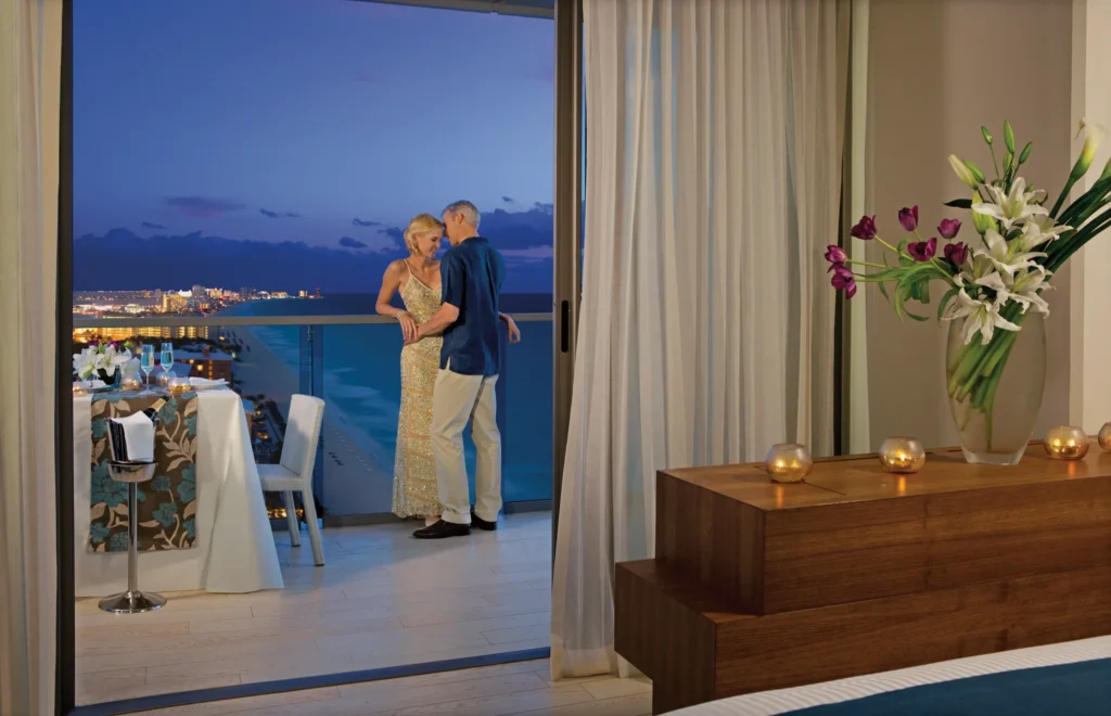 Couple enjoying private in-room dining on a balcony overlooking Cancun’s Hotel Zone at Secrets The Vine Cancun.