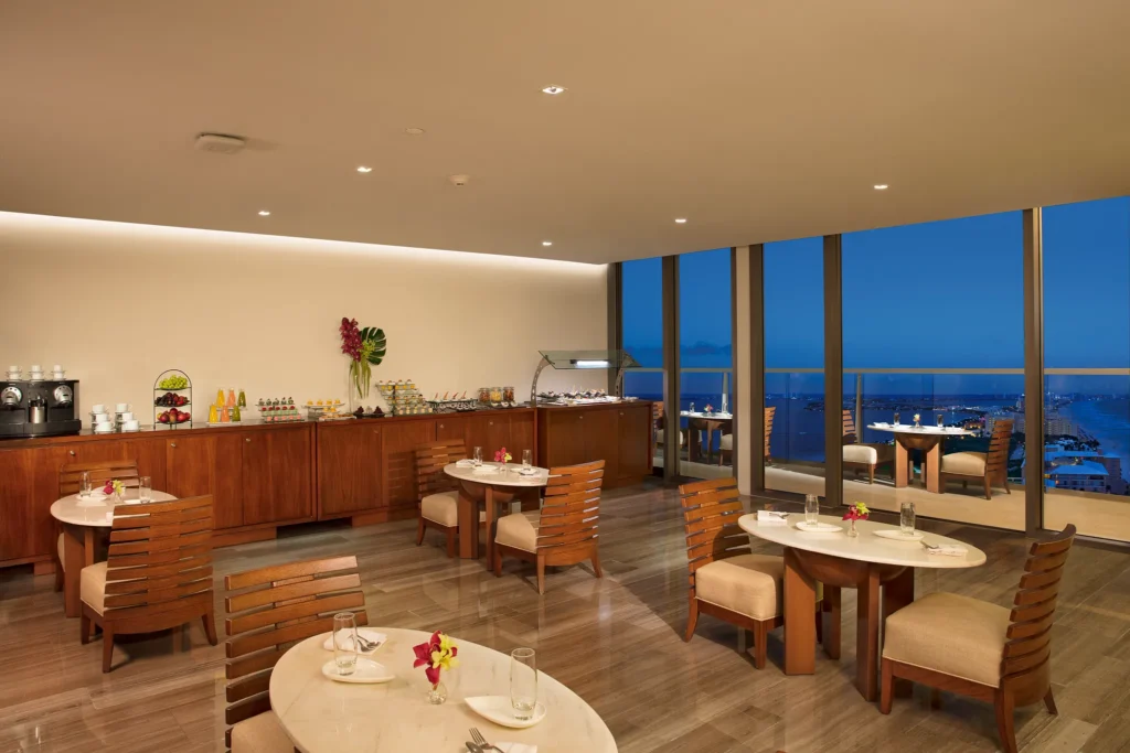 Elegant indoor lounge with light bites and ocean-view terrace at Secrets The Vine Cancun, ideal for relaxing in a luxury adults-only resort.