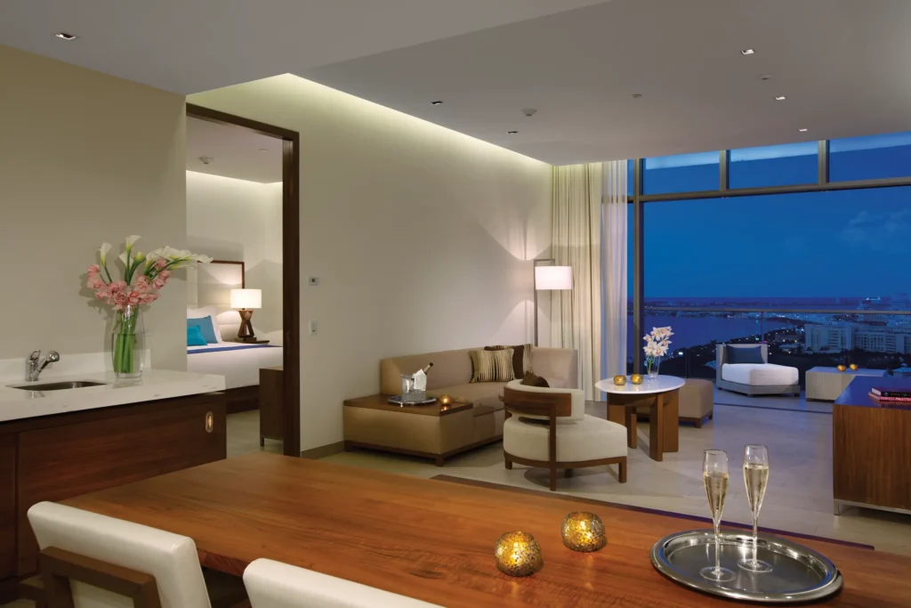 Preferred Club Governor Suite living and dining area with sofa, dining table, and ocean view balcony at Secrets The Vine Cancun.