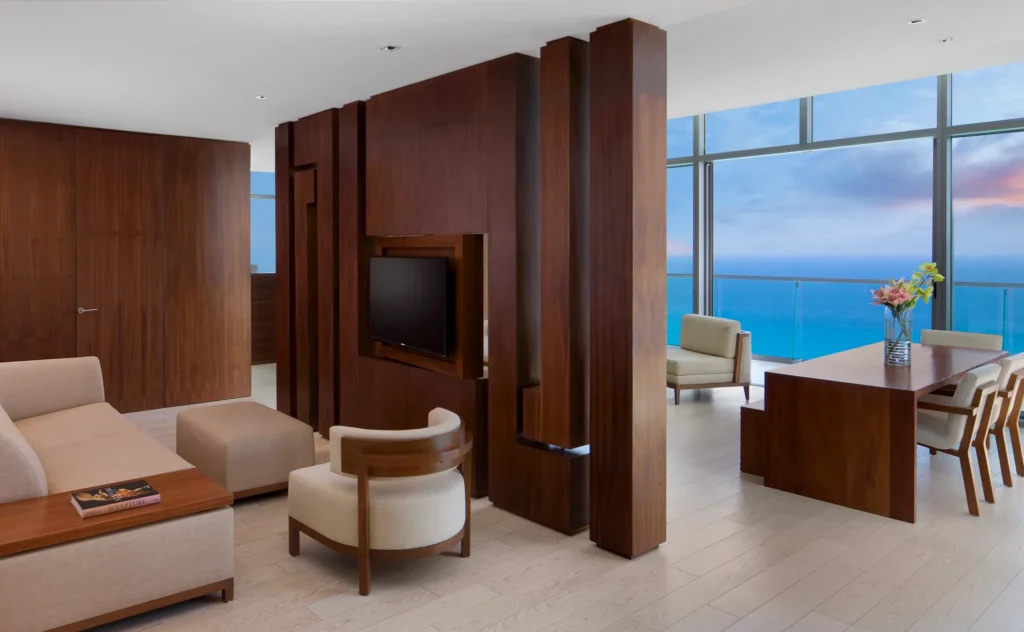 Preferred Club Master Suite Ocean Front living area with sofa, dining table, and oceanfront balcony views at Secrets The Vine Cancun.