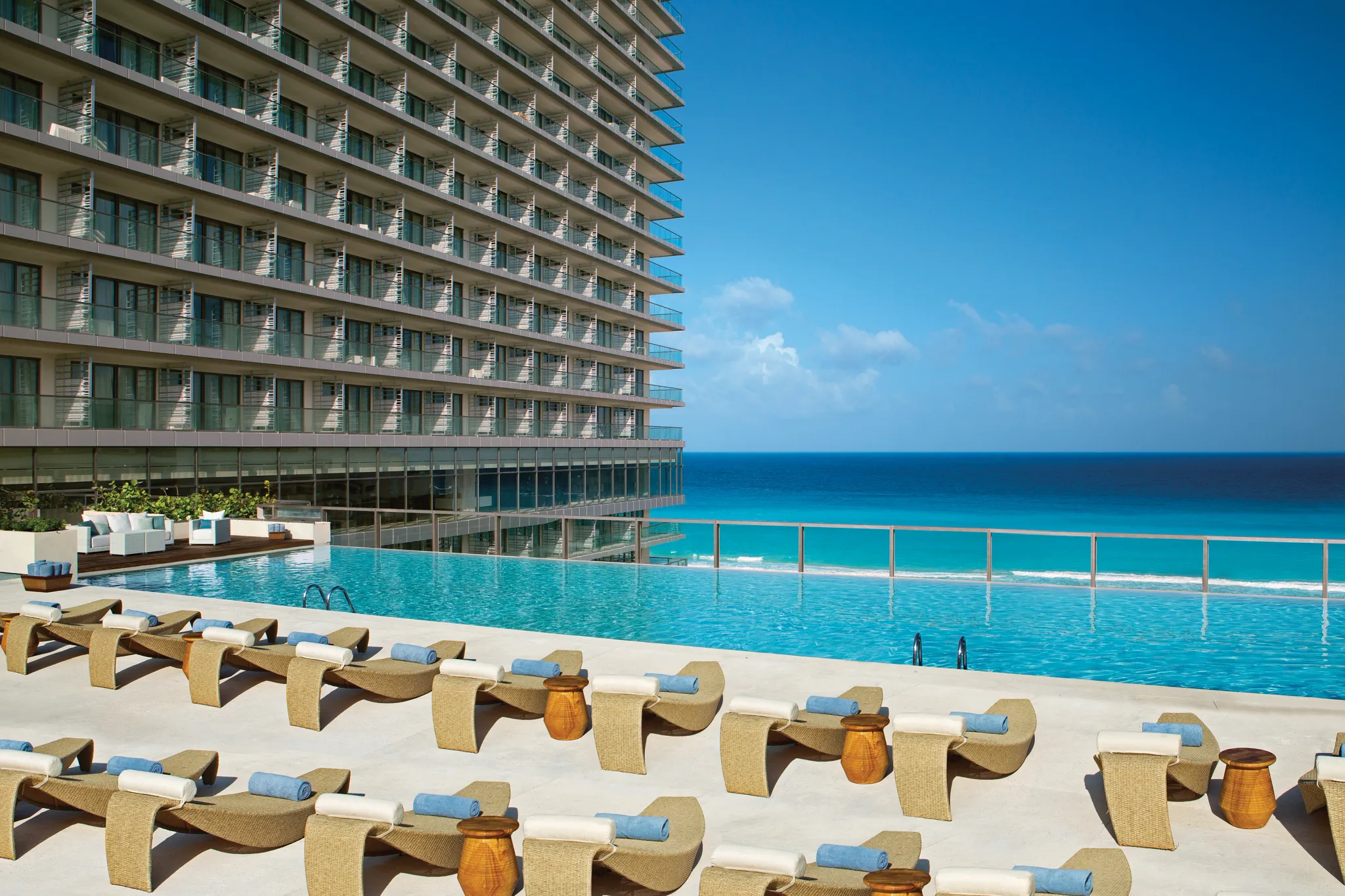 Preferred Club infinity pool with luxury loungers overlooking the Caribbean Sea at Secrets The Vine Cancun.