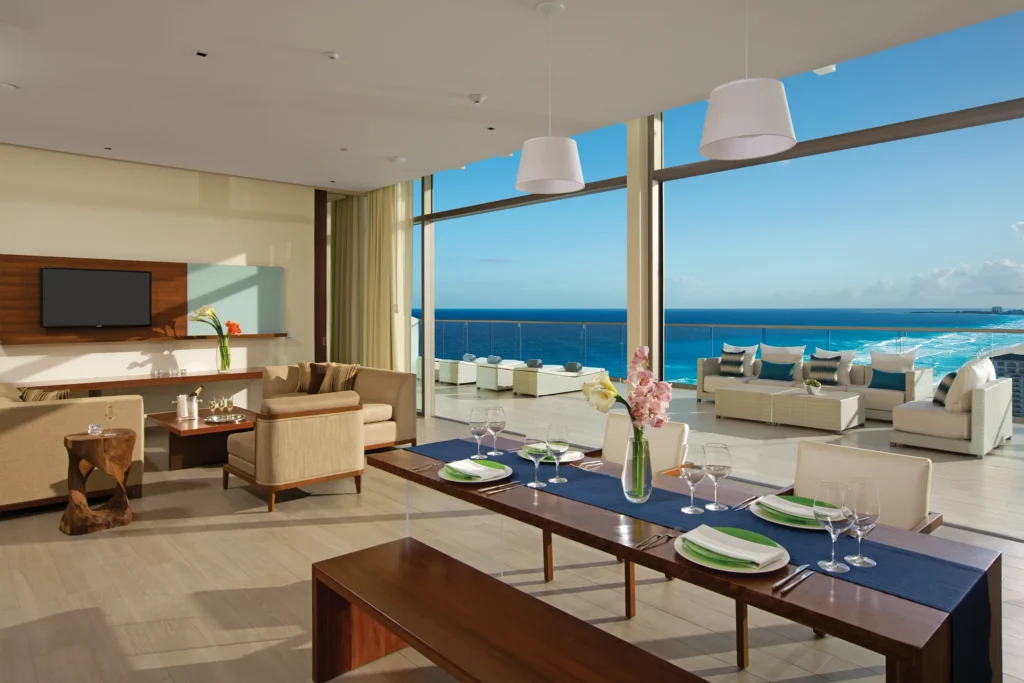 Preferred Club Presidential Suite dining table and living room with ocean view terrace at Secrets The Vine Cancun.