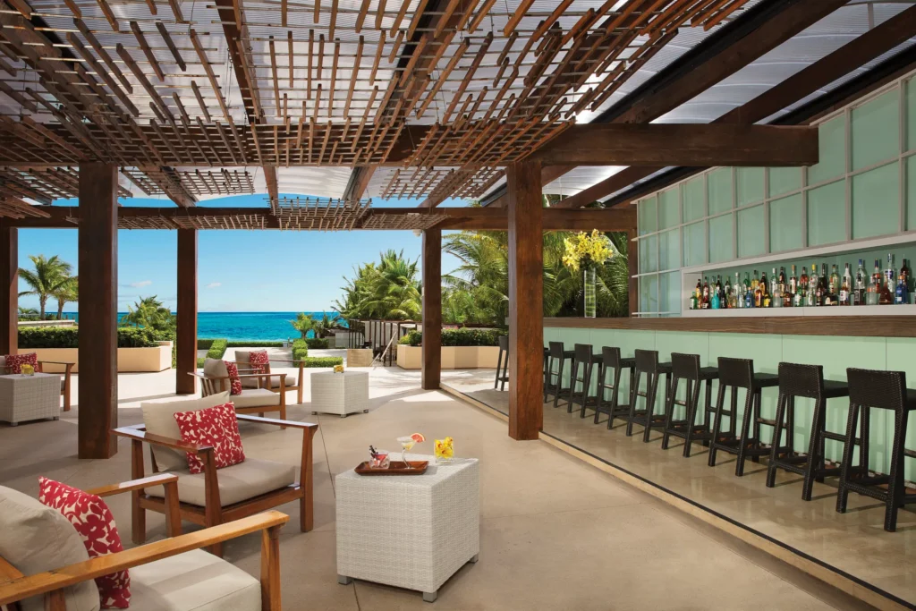 The Vine Lounge and Terrace Bar at Secrets The Vine Cancun featuring an elegant lobby bar with ocean views, cocktails, and stylish seating.