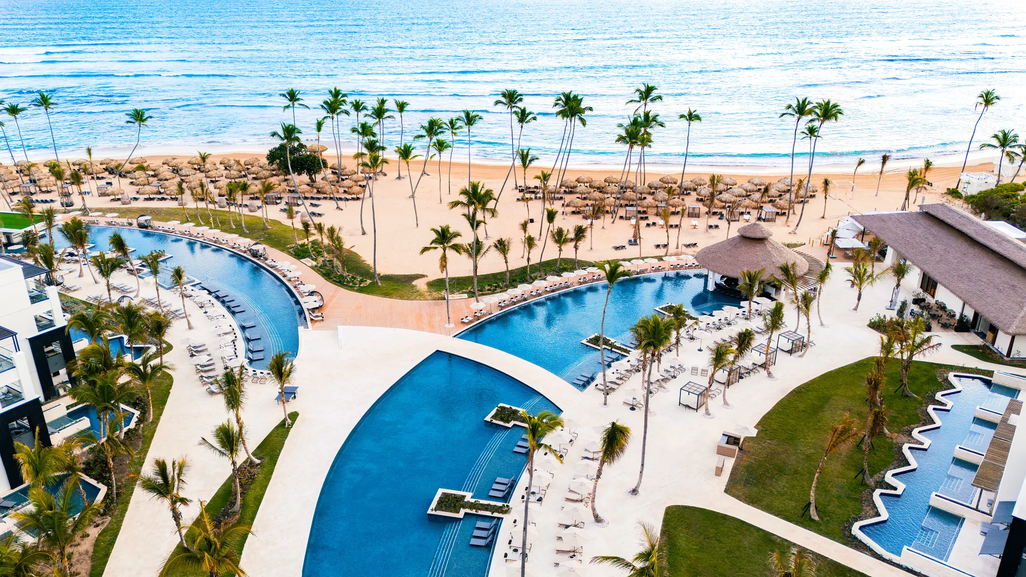 Aerial view of Secrets Tides Punta Cana with beachfront pools, palm trees, and white sand beach along the Caribbean Sea.