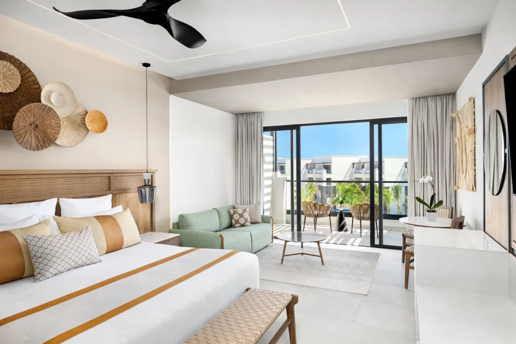 Junior Suite Partial Ocean View with king bed and balcony at Secrets Tides Punta Cana overlooking tropical grounds and partial ocean views.