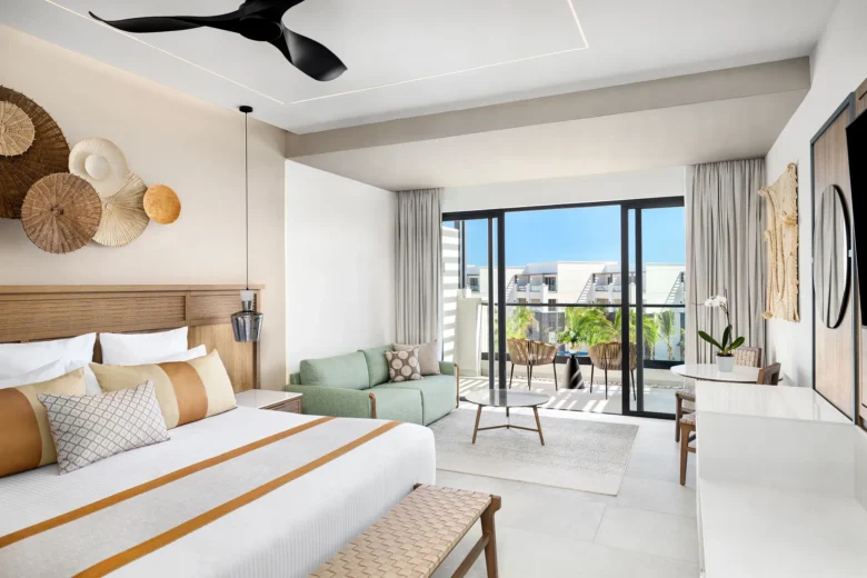 Junior Suite Partial Ocean View with king bed and balcony at Secrets Tides Punta Cana overlooking tropical grounds and partial ocean views.