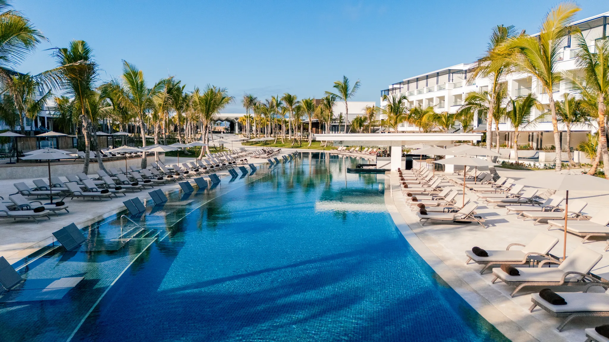 Main infinity pool at Secrets Tides Punta Cana with lounge chairs, palm trees, and swim-up bar in a tropical setting.