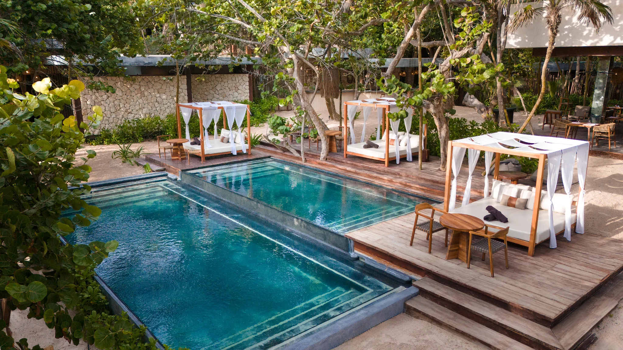 Private pool with luxury cabanas surrounded by tropical gardens at Casa Zamna Beach Club, part of Secrets Tulum Resort & Beach Club.