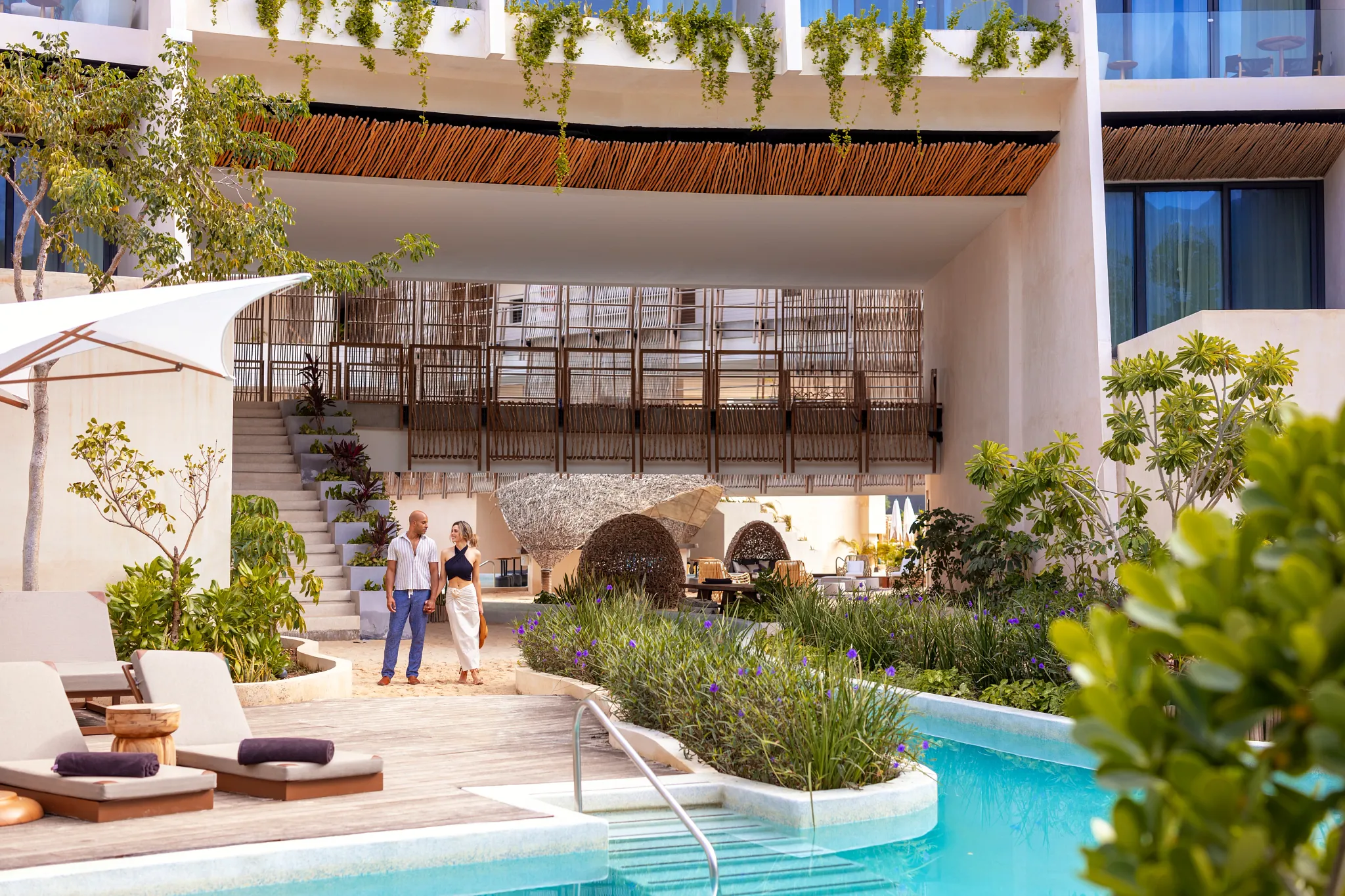 Couple walking beside the lagoon-style pool at Secrets Tulum Resort & Beach Club.