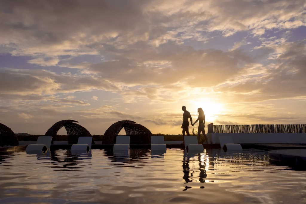 Couple walking beside the rooftop pool at sunset at Secrets Tulum Resort & Beach Club.