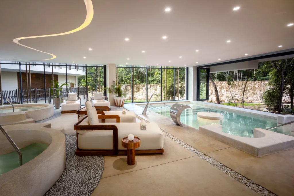 Indoor hydrotherapy pool with whirlpools and relaxation loungers at Secrets Spa by Pevonia® in Tulum.
