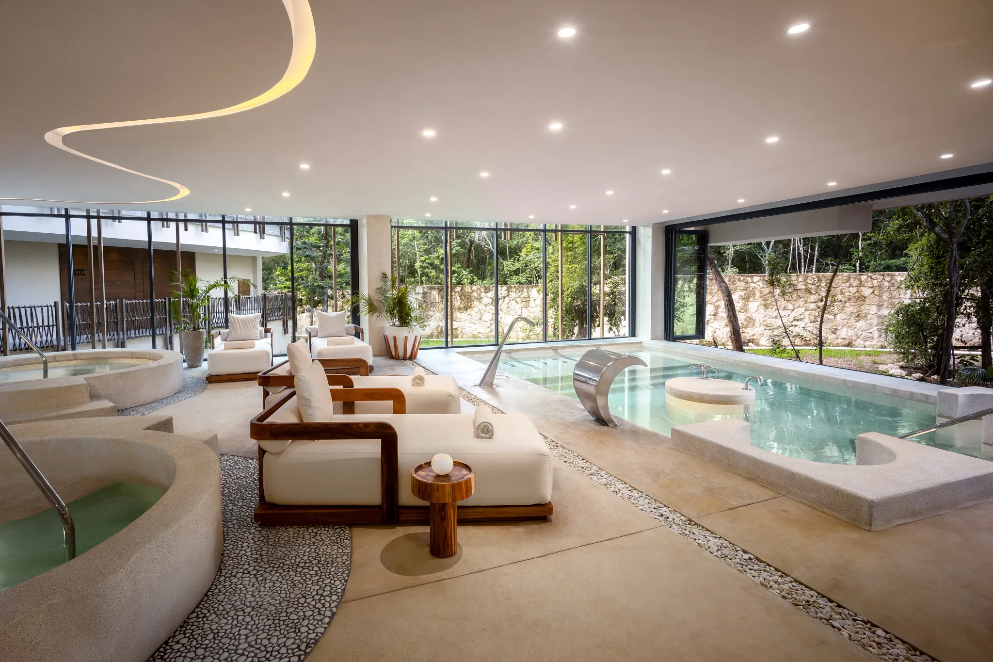 Indoor hydrotherapy pool with whirlpools and relaxation loungers at Secrets Spa by Pevonia® in Tulum.