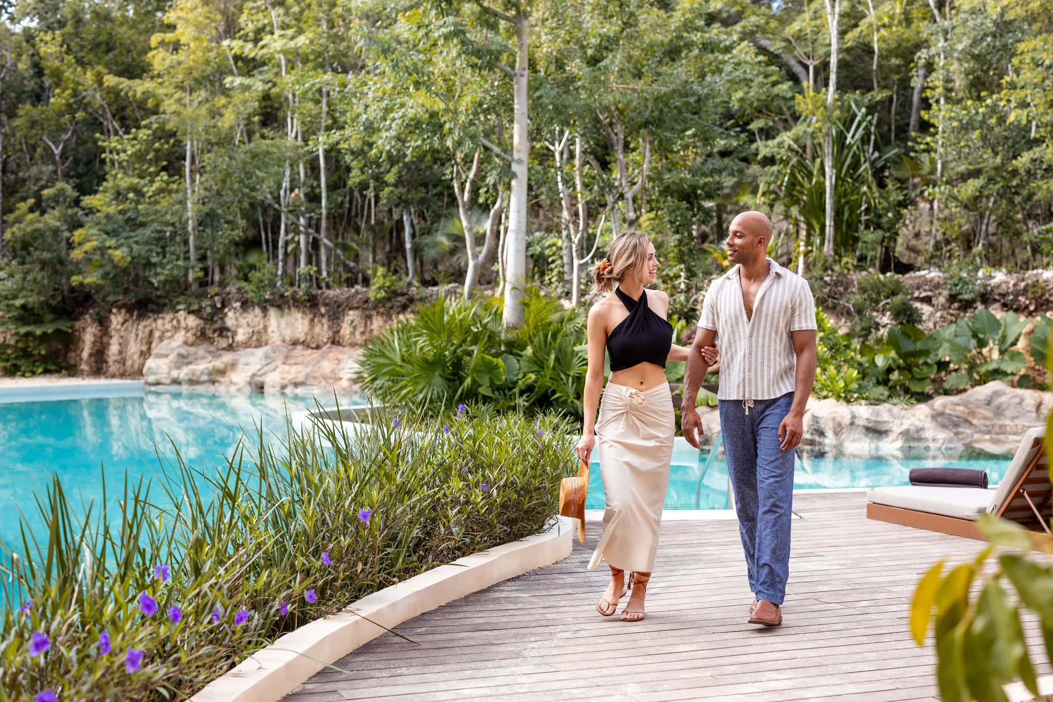 Couple walking along the lagoon-style pool surrounded by lush tropical gardens at Secrets Tulum Resort & Beach Club.