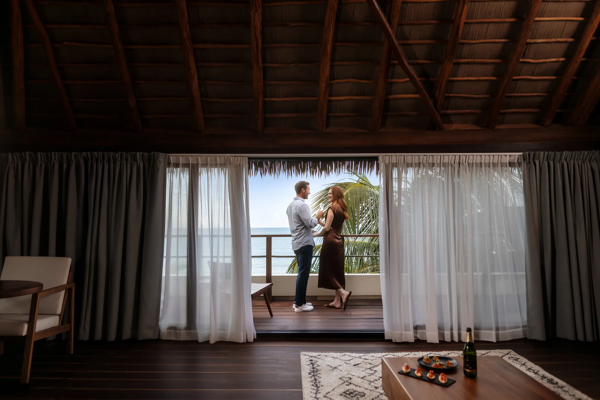 Couple enjoying an ocean-view balcony at Casa Zamna Beach Club in Tulum.