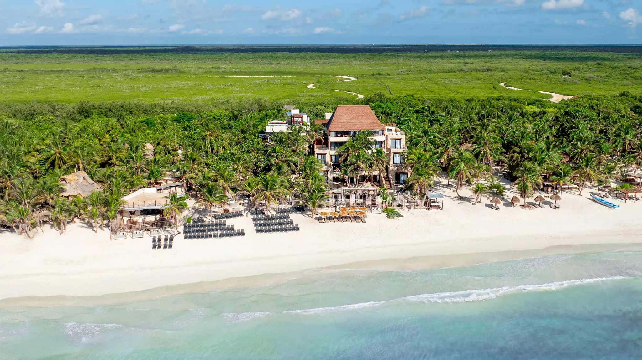 Overhead aerial view of Casa Zamna Beach Club with pools, palm trees, and beachfront cabanas.