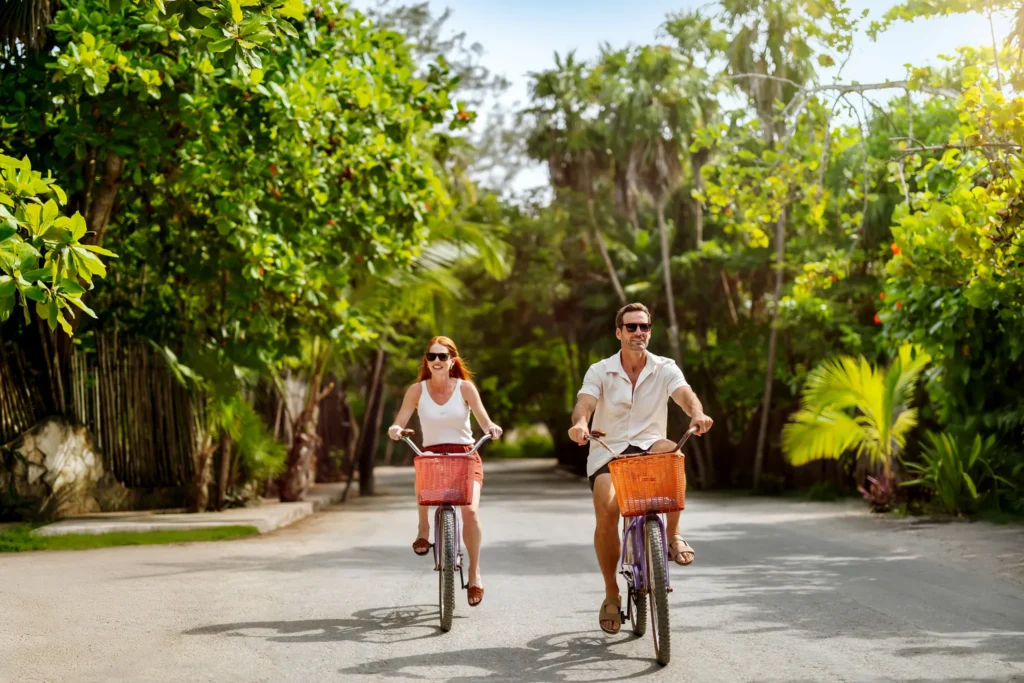 Couple riding bicycles through tropical pathways at Secrets Tulum Resort & Beach Club.