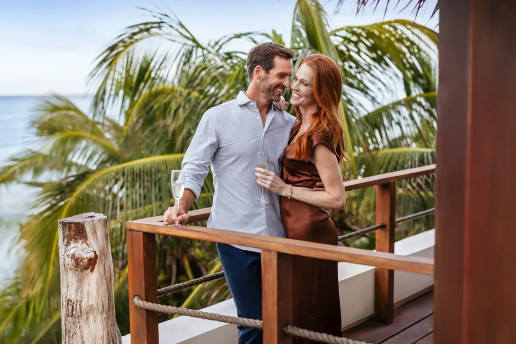 Couple enjoying champagne on a private balcony overlooking the Caribbean Sea at Casa Zamna Beach Club.