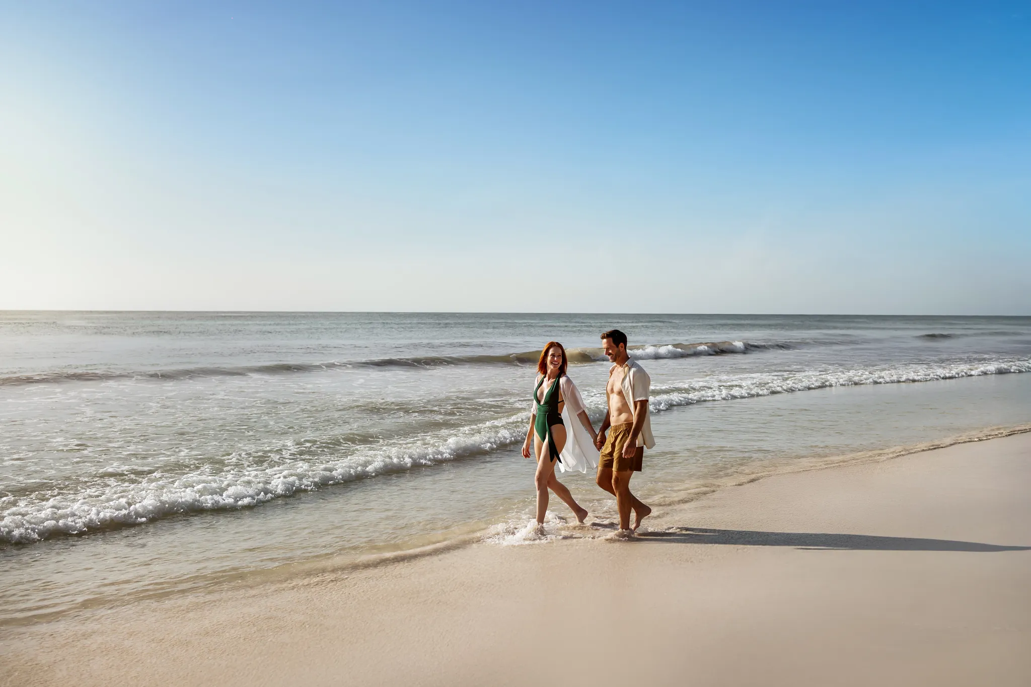 Couple walking along the white-sand beach at Casa Zamna Beach Club in Tulum.