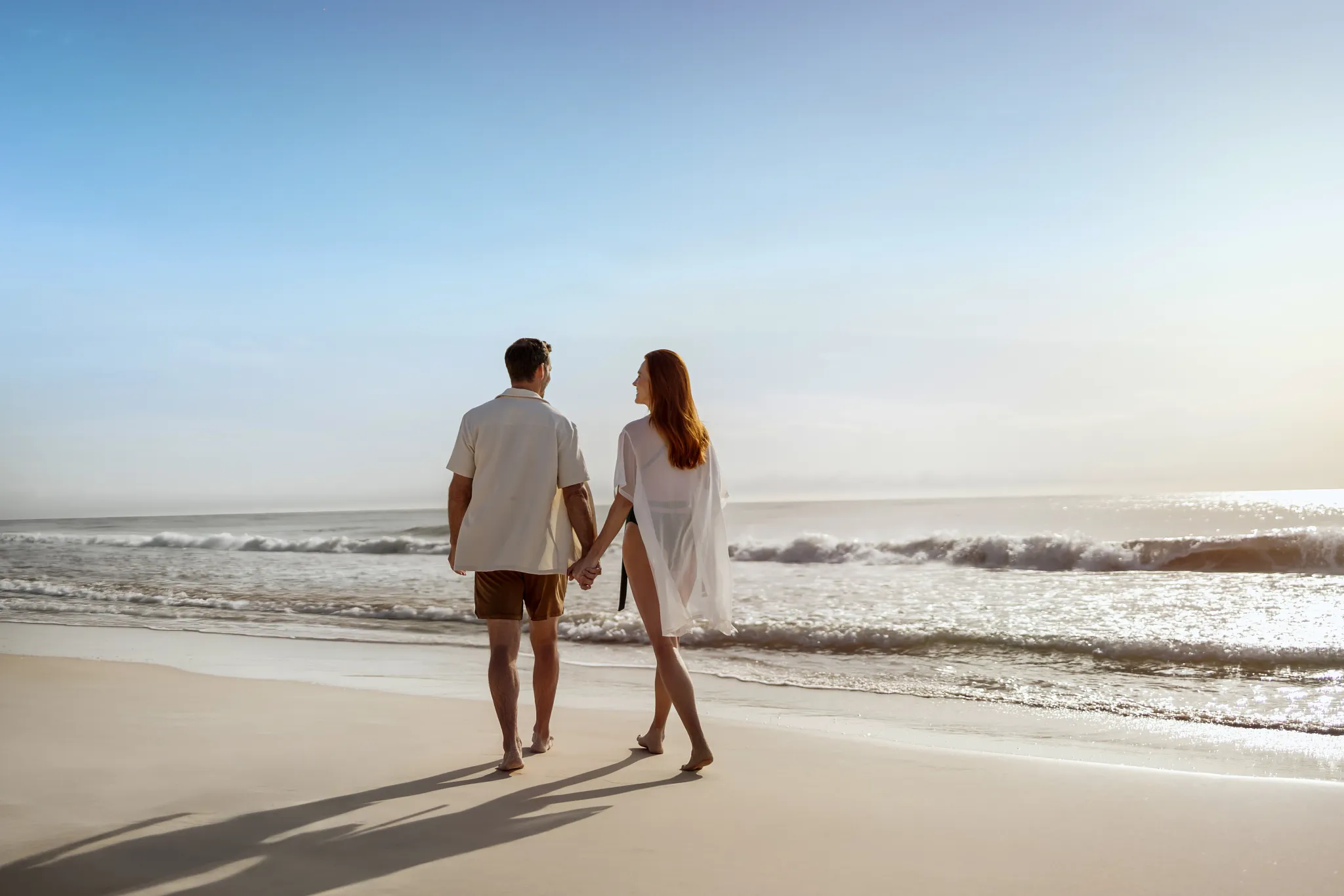 Couple walking hand in hand along the beach at Secrets Tulum Resort & Beach Club during sunset.