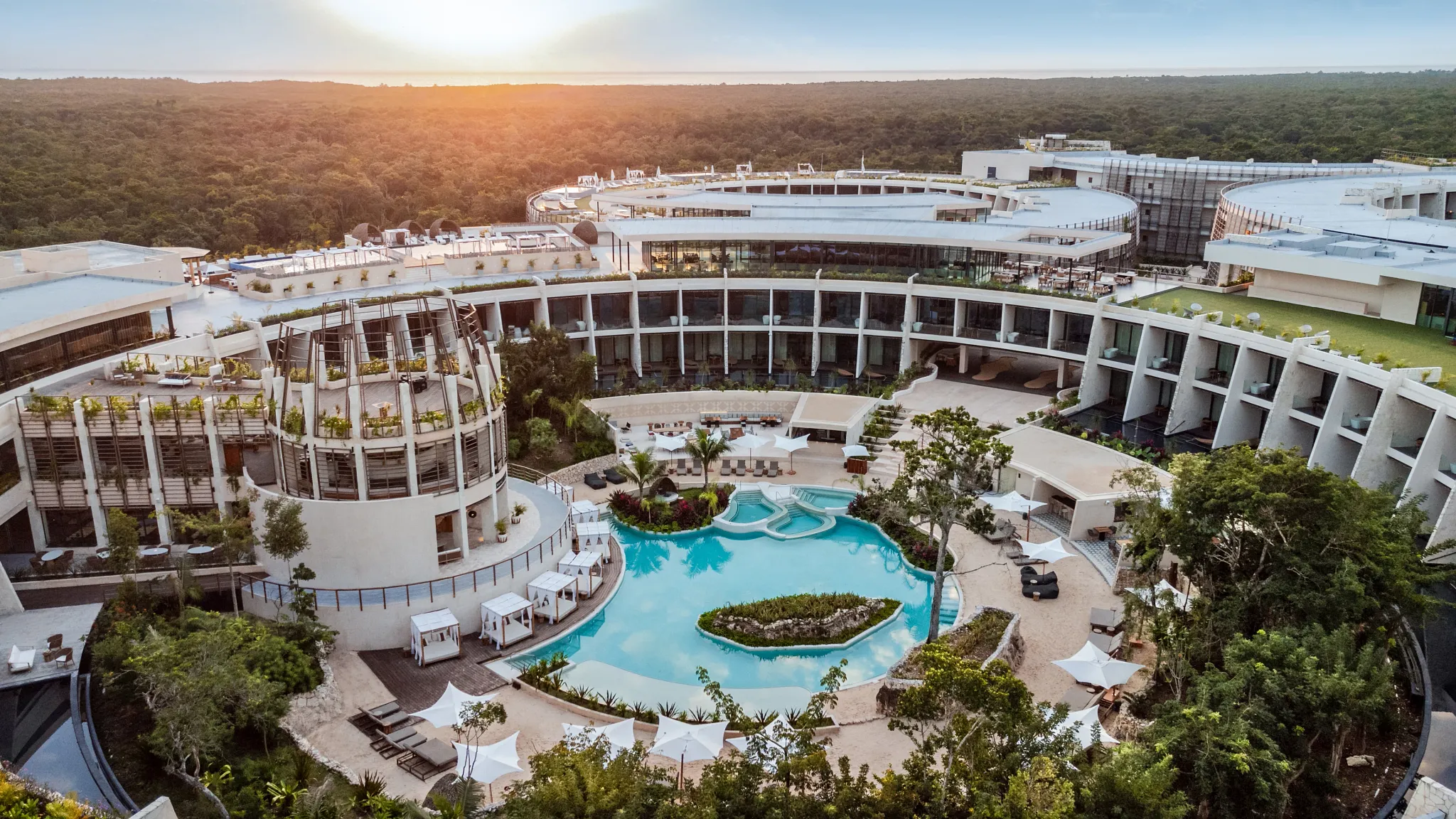 Aerial view of Secrets Tulum Resort & Beach Club showcasing modern architecture, lush jungle surroundings, and the resort's central pool.
