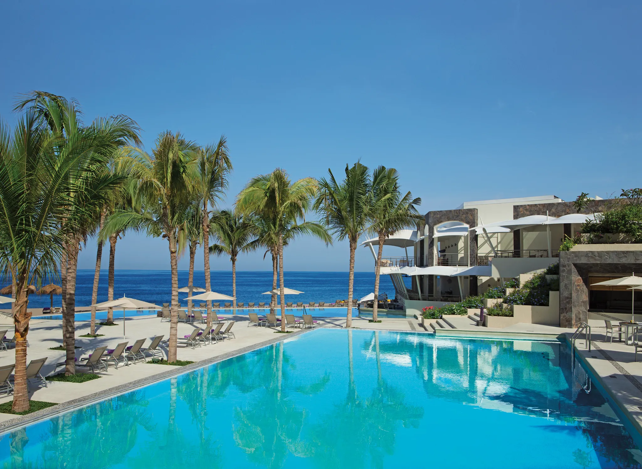 Resort pool and beachfront area with lounge chairs and umbrellas at Secrets Vallarta Bay Puerto Vallarta.