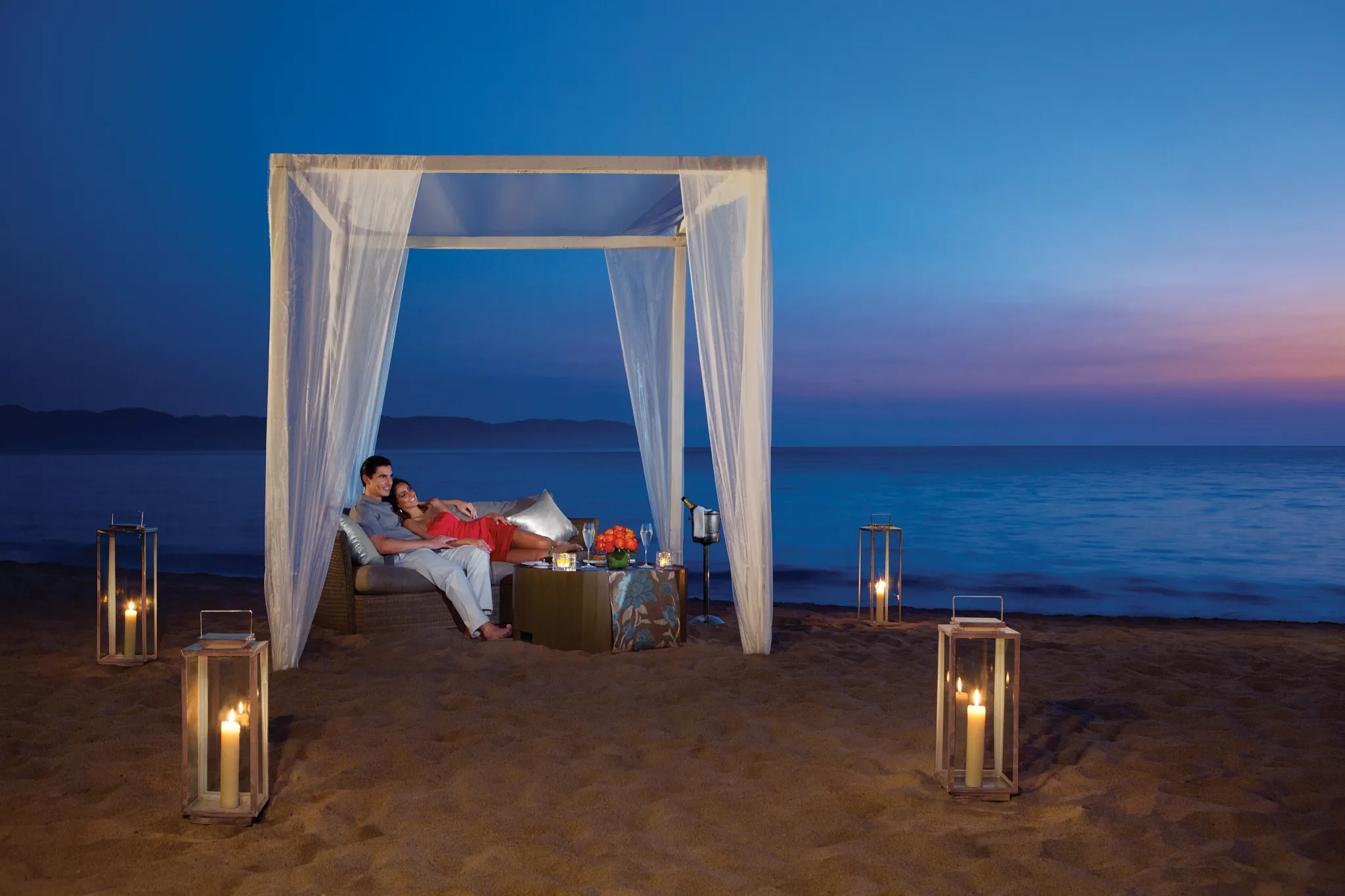Couple enjoying a private candlelit beach dinner under a cabana at Secrets Vallarta Bay Puerto Vallarta.
