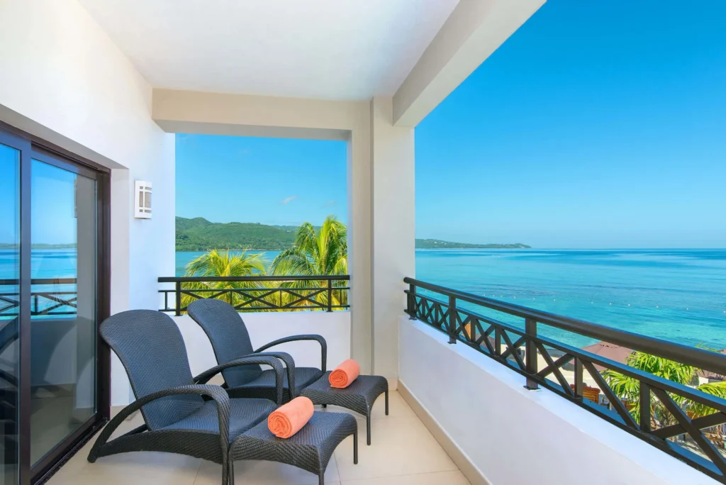 Preferred Club Master Suite Oceanfront balcony with lounge chairs and Caribbean sea views at Secrets Wild Orchid Montego Bay.