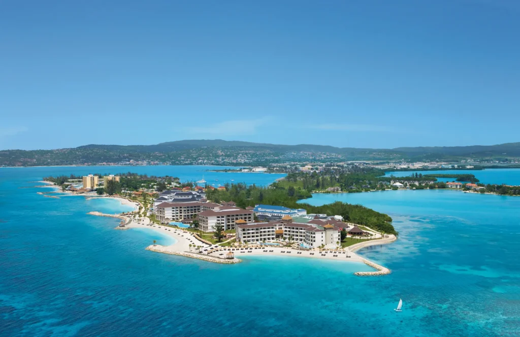 Aerial coastline view of Secrets Wild Orchid Montego Bay with turquoise waters and beachfront pools in Jamaica.